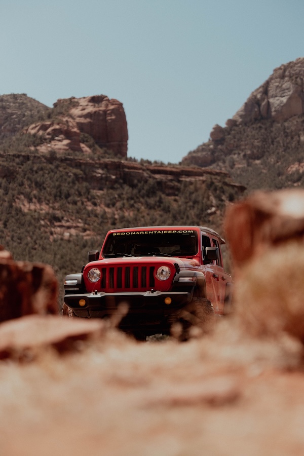 A red Jeep on a Sedona off-road trail framed by red rock formations